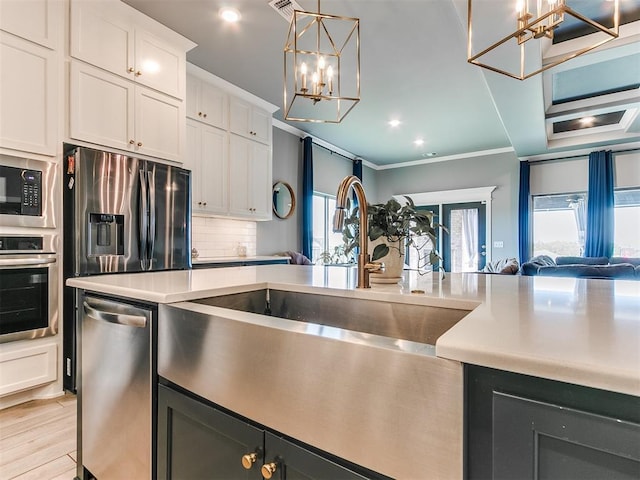 kitchen with a sink, open floor plan, appliances with stainless steel finishes, ornamental molding, and decorative backsplash