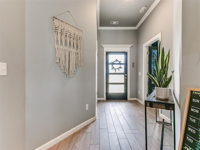 foyer with baseboards, crown molding, visible vents, and wood finished floors