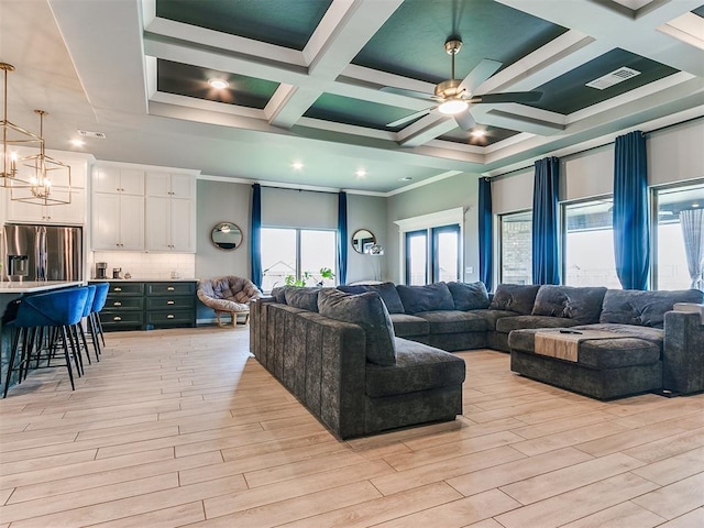 living area with ceiling fan with notable chandelier, coffered ceiling, visible vents, and light wood-style floors