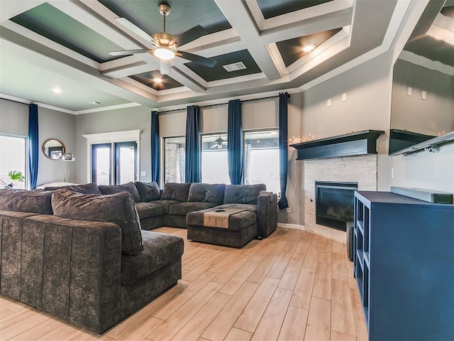 living room with crown molding, visible vents, a stone fireplace, light wood-type flooring, and coffered ceiling