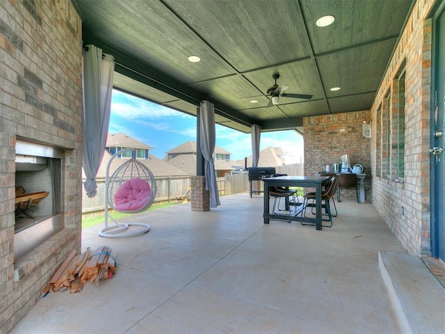 view of patio with ceiling fan, fence, outdoor dining area, and an outdoor brick fireplace