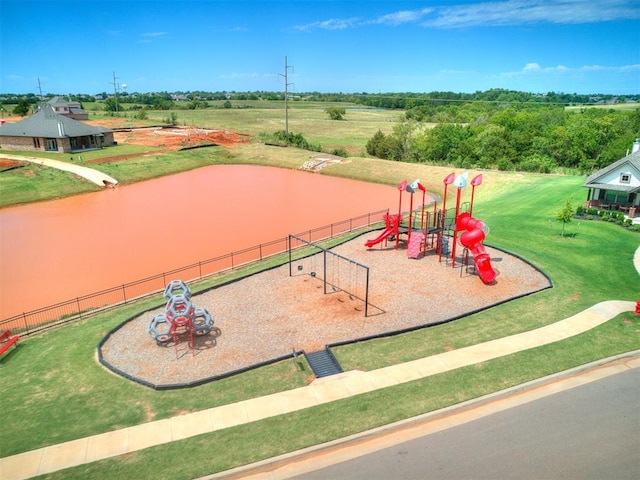 community play area featuring a water view, fence, and a lawn