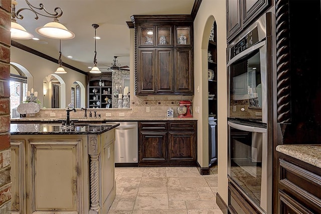 kitchen featuring stone tile floors, decorative backsplash, dark brown cabinetry, appliances with stainless steel finishes, and crown molding