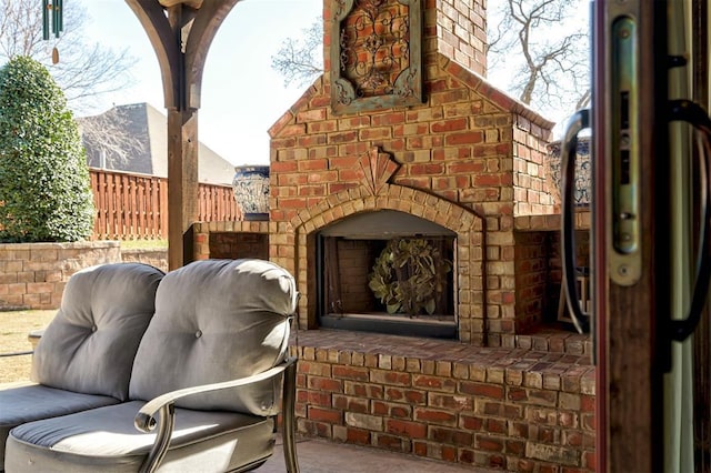 view of patio / terrace with an outdoor brick fireplace and fence