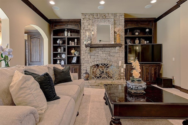 living room featuring crown molding, built in shelves, a fireplace, and arched walkways