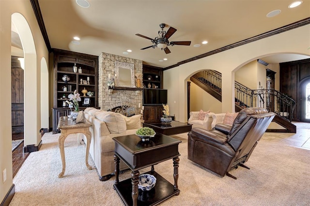 carpeted living room featuring stairs, a fireplace, arched walkways, and a ceiling fan