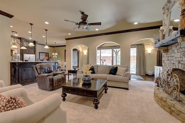 living room with crown molding, carpet flooring, a fireplace, and arched walkways