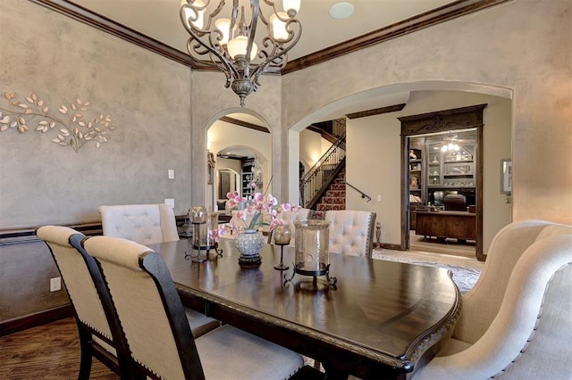 dining space featuring a notable chandelier, ornamental molding, wood finished floors, arched walkways, and baseboards