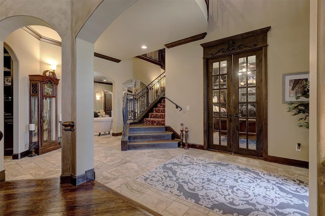 entrance foyer featuring ornamental molding, french doors, arched walkways, stairway, and baseboards