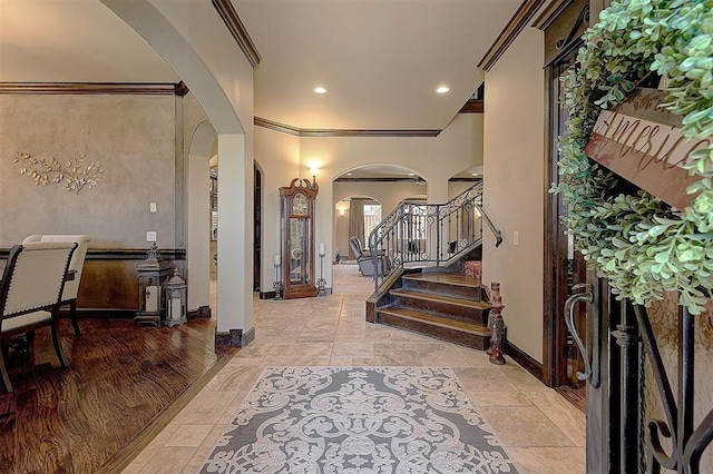 foyer entrance featuring ornamental molding, recessed lighting, arched walkways, baseboards, and stairs