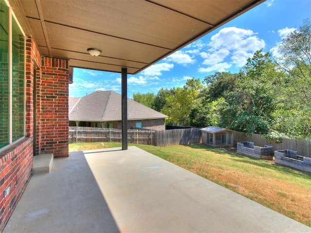 view of patio / terrace with an outbuilding, a fenced backyard, and a vegetable garden