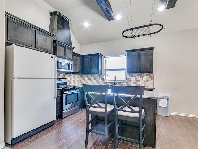 kitchen featuring lofted ceiling, stainless steel appliances, a kitchen breakfast bar, tasteful backsplash, and dark wood finished floors