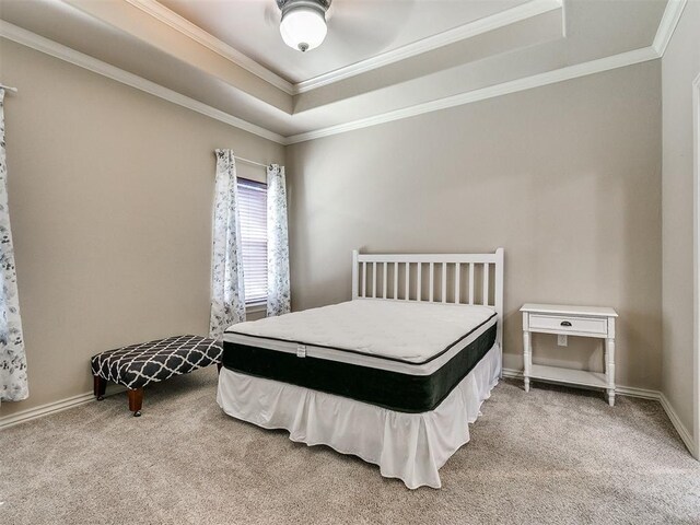 bedroom with carpet floors, baseboards, a tray ceiling, and crown molding