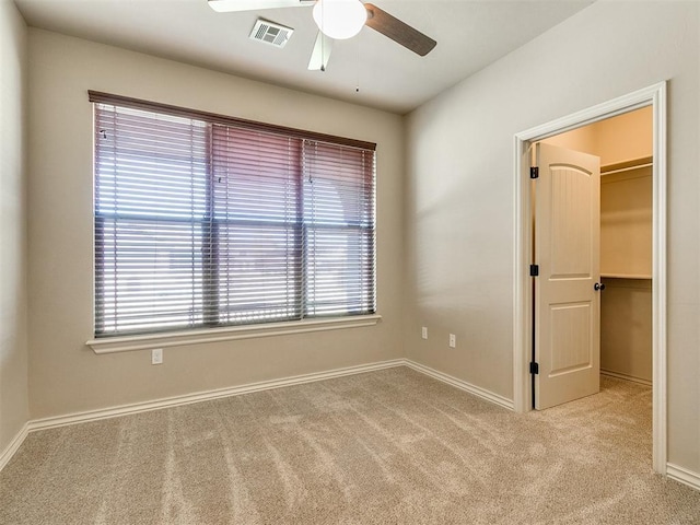 empty room featuring light colored carpet, visible vents, ceiling fan, and baseboards