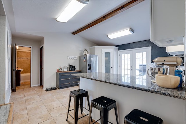 kitchen with a breakfast bar, french doors, vaulted ceiling with beams, blue cabinets, and stainless steel fridge with ice dispenser