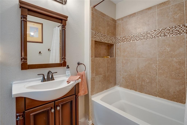 bathroom featuring a textured wall, shower / tub combo with curtain, and vanity