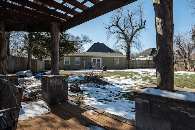 snow covered deck featuring a fenced backyard and a pergola