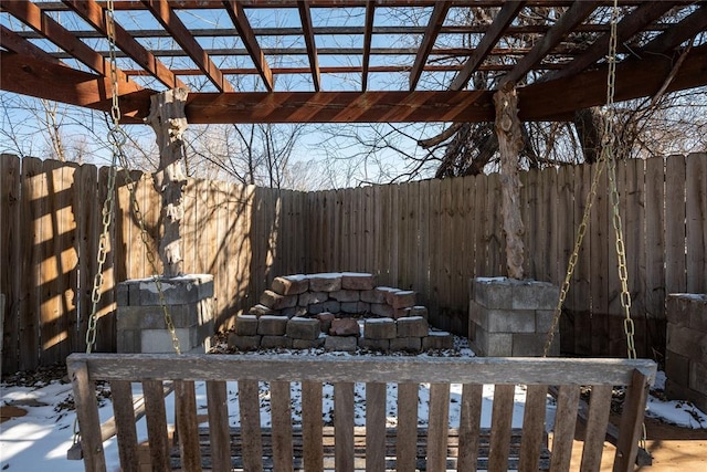 snow covered patio with a fenced backyard and a pergola