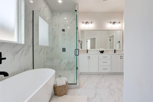 bathroom featuring marble finish floors, a marble finish shower, a freestanding tub, double vanity, and recessed lighting