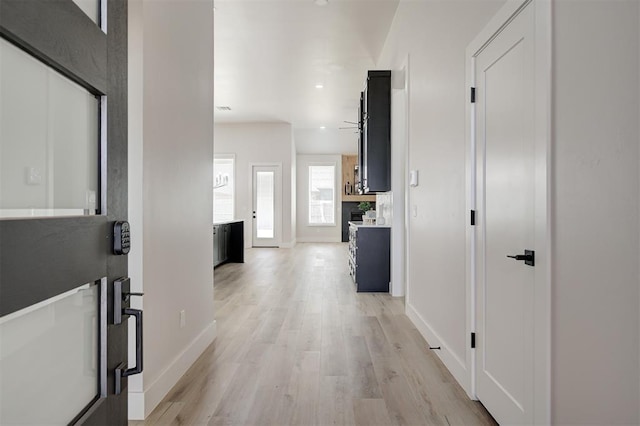 corridor featuring baseboards, light wood-type flooring, and recessed lighting