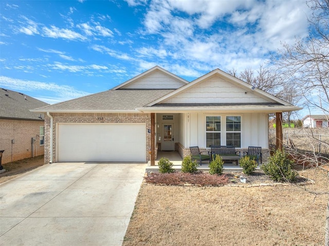 view of front of house with an attached garage, covered porch, brick siding, driveway, and roof with shingles