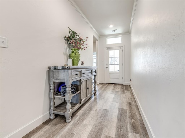 doorway featuring ornamental molding, visible vents, baseboards, and wood finished floors