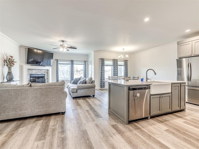 kitchen featuring stainless steel appliances, open floor plan, light countertops, and a center island with sink