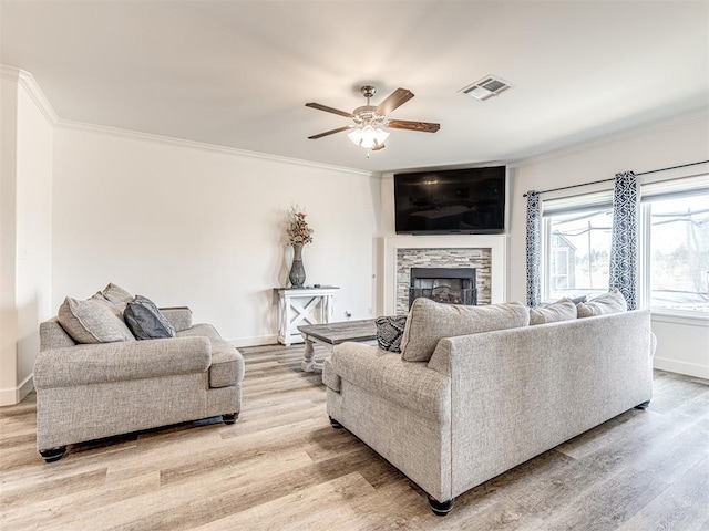 living room with light wood-style flooring, visible vents, ornamental molding, and a fireplace