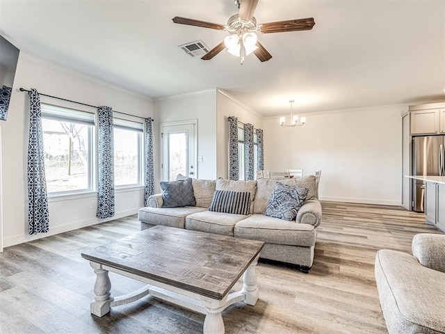 living area with light wood finished floors, baseboards, visible vents, and crown molding