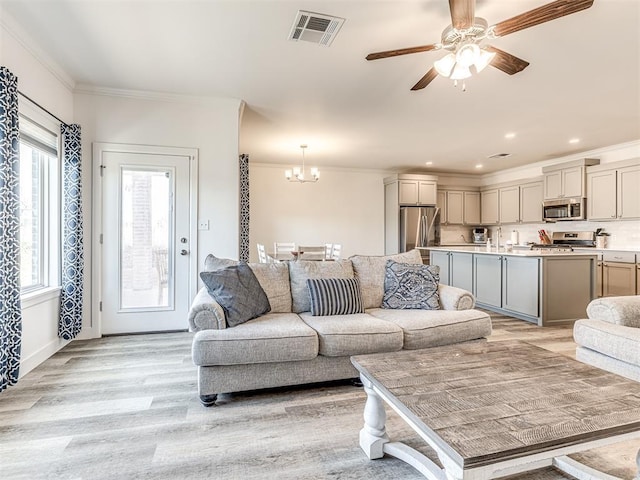 living room with recessed lighting, visible vents, ornamental molding, light wood-style floors, and ceiling fan with notable chandelier