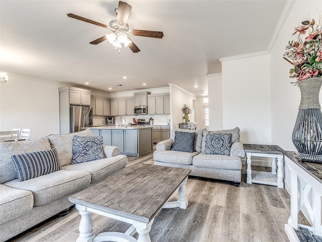 living room with ceiling fan, recessed lighting, light wood-type flooring, and crown molding