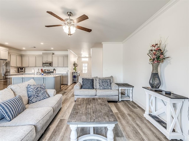 living room featuring baseboards, light wood finished floors, a ceiling fan, and crown molding