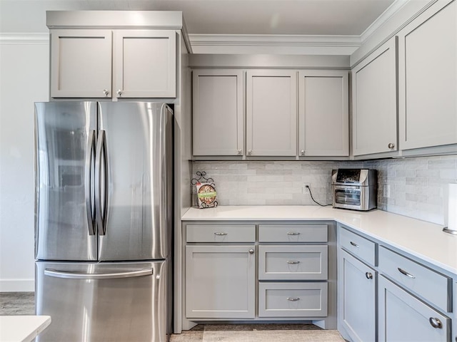 kitchen featuring freestanding refrigerator, gray cabinets, light countertops, and crown molding