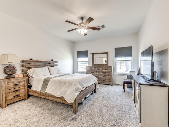 bedroom with light colored carpet, ceiling fan, visible vents, and baseboards