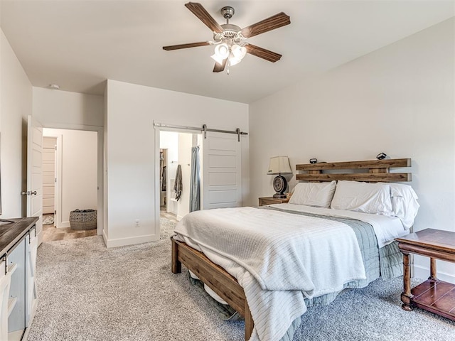 bedroom with light colored carpet, ceiling fan, baseboards, and a barn door