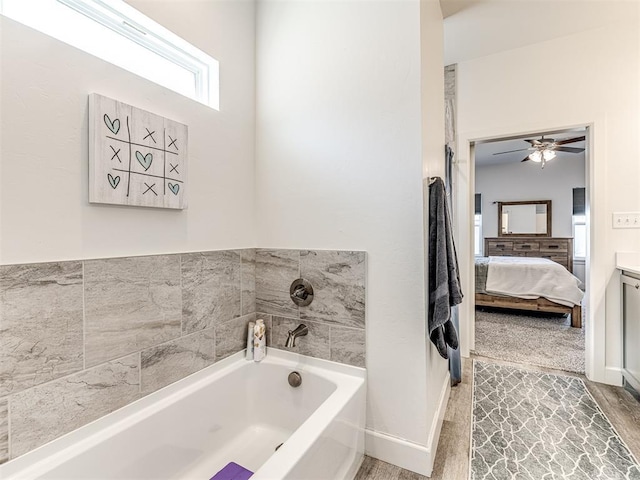 full bath with baseboards, connected bathroom, wood finished floors, a garden tub, and vanity