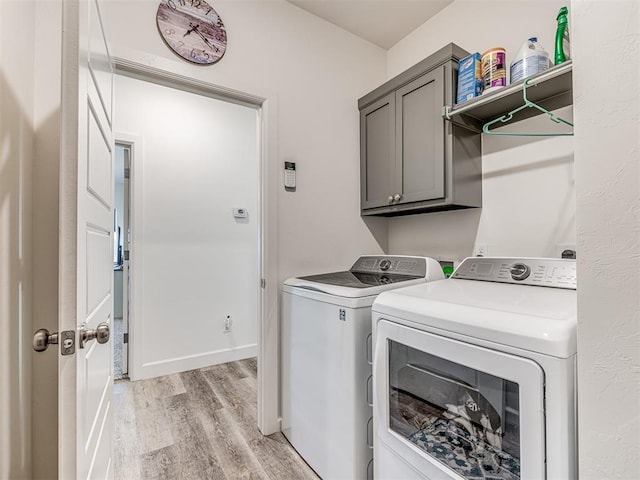 laundry room with baseboards, independent washer and dryer, cabinet space, and light wood-style floors