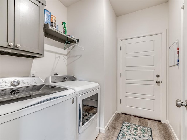 clothes washing area featuring baseboards, washing machine and clothes dryer, cabinet space, and light wood-style floors