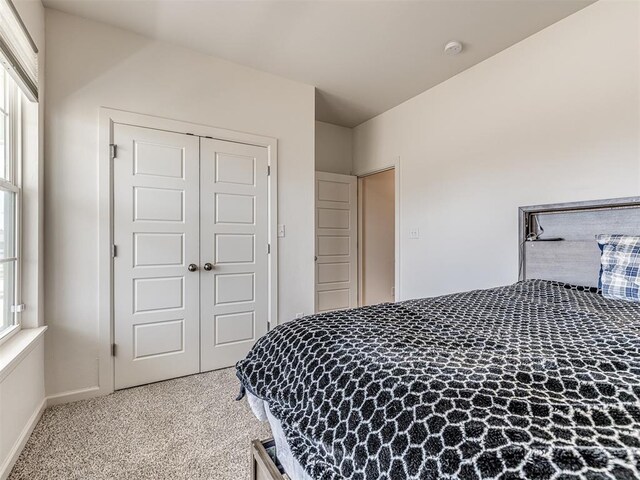 carpeted bedroom featuring multiple windows, baseboards, and a closet