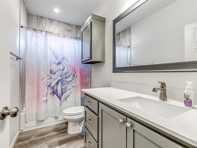 bathroom with toilet, shower / bath combination with curtain, wood finished floors, and vanity