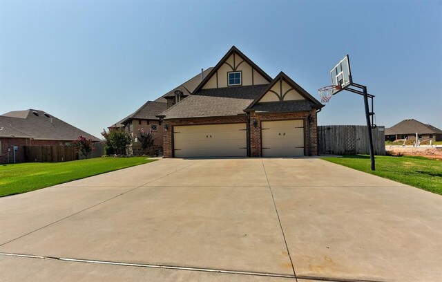 view of front facade featuring an attached garage, fence, a front lawn, and brick siding