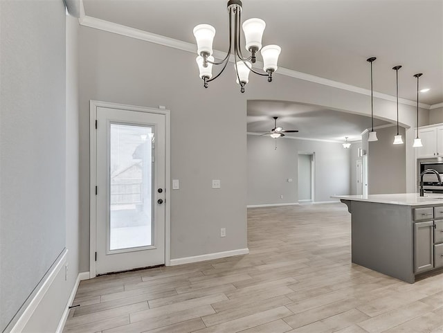 kitchen featuring pendant lighting, crown molding, light countertops, light wood-style flooring, and open floor plan
