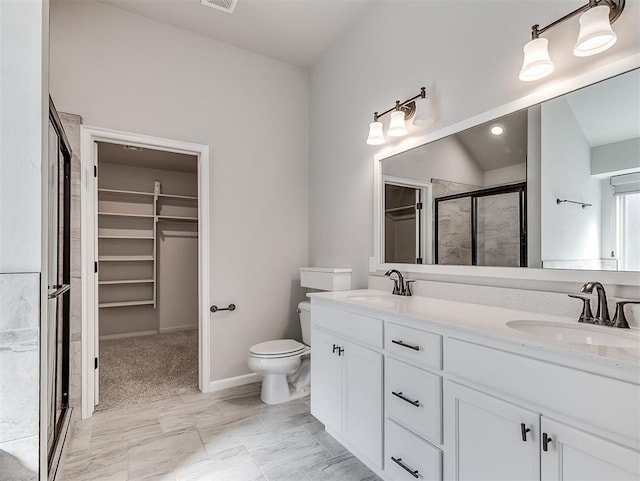 full bathroom featuring double vanity, a shower stall, a walk in closet, and a sink