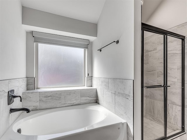 bathroom featuring a stall shower and a bath