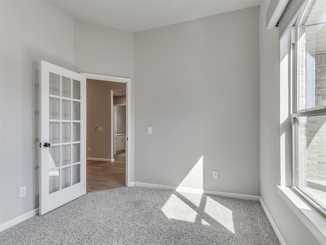 unfurnished room featuring carpet floors, french doors, and baseboards