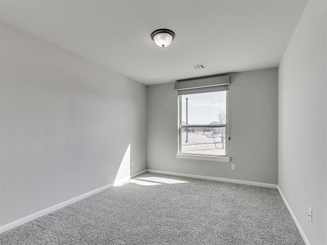 empty room featuring carpet, visible vents, and baseboards