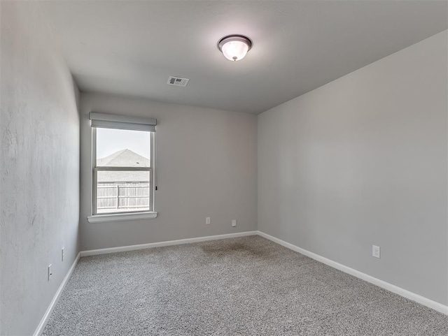 empty room featuring carpet floors, baseboards, and visible vents