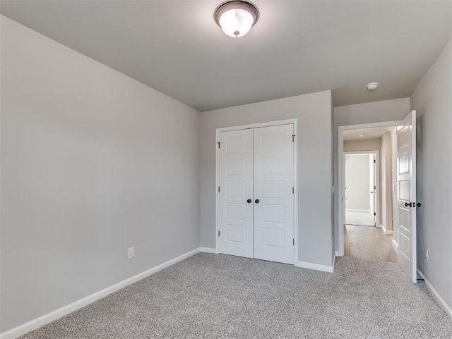 unfurnished bedroom with light carpet, baseboards, and a closet