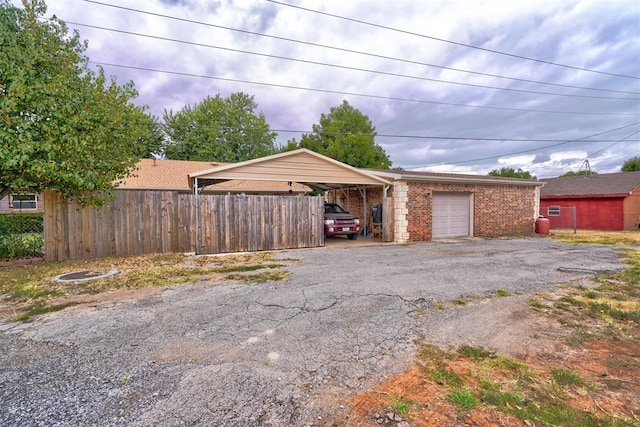 garage with a carport, aphalt driveway, and fence