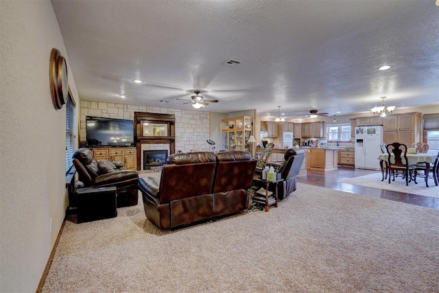 living room with light carpet, visible vents, a textured wall, a textured ceiling, and a fireplace